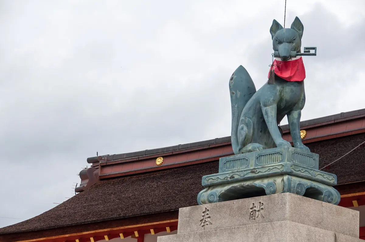 A fox statue holding a key at Fushimi Inari